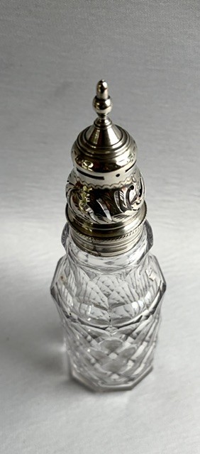 An 18th-century Georgian clear glass caster featuring diamond cut facets and a silver pierced cap with a finial. View VII
