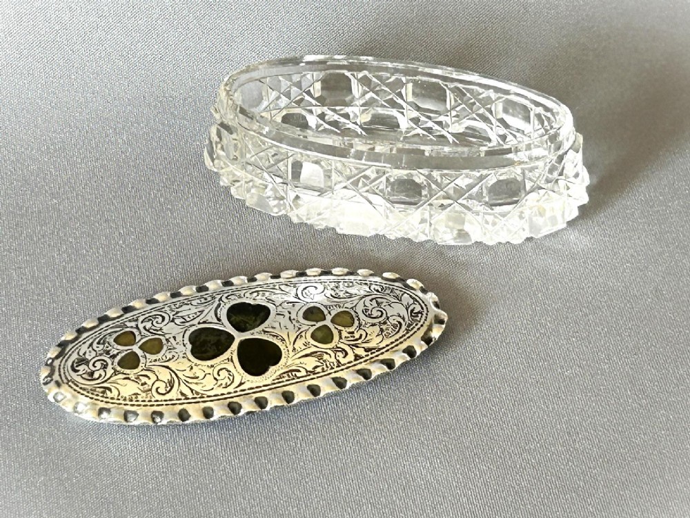 An oval Edwardian cut glass trinket box featuring an engraved sterling silver lid inset with green Connemara marble shamrock shapes. View IV