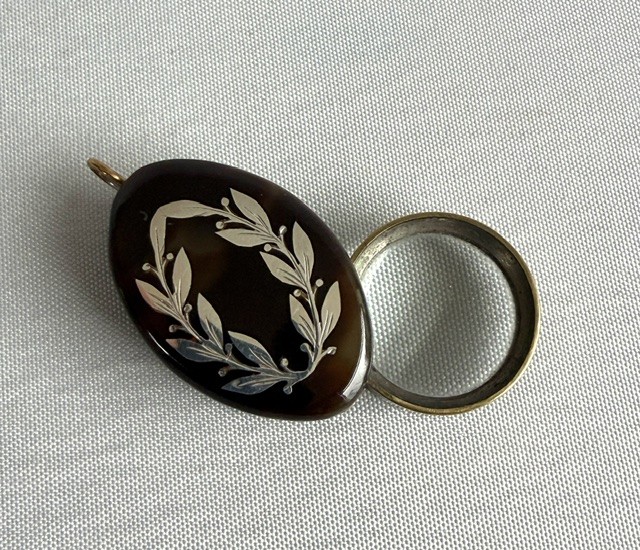 A Victorian oval dark brown tortoiseshell folding loupe decorated with silver pique foliate inlay and featuring a swivelling circular magnifying glass lens. View III