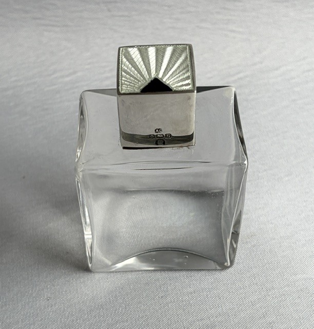 An Art Deco clear glass cologne bottle featuring a cubic silver cap with engine-turned sunburst detailing. View III