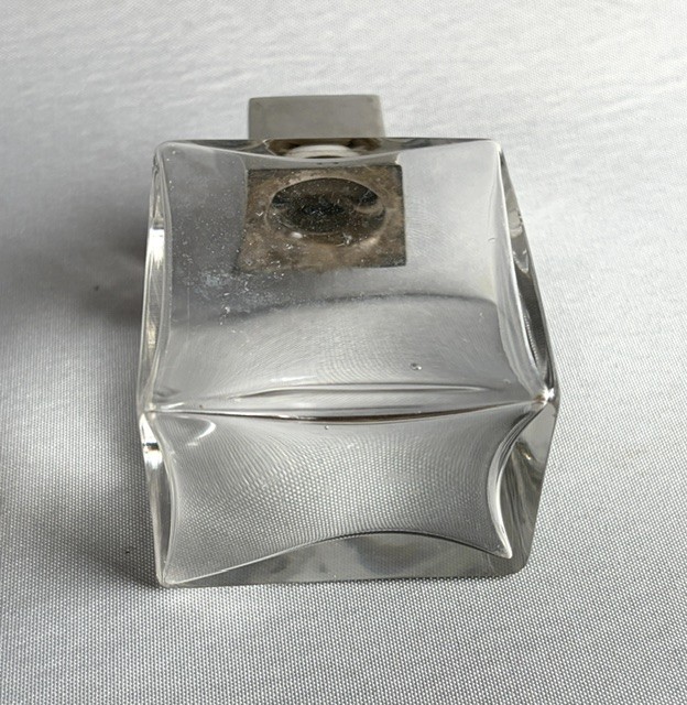 An Art Deco clear glass cologne bottle featuring a cubic silver cap with engine-turned sunburst detailing. View IV