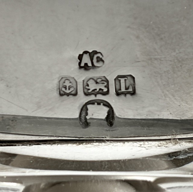 An Art Deco clear glass cologne bottle featuring a cubic silver cap with engine-turned sunburst detailing. View V