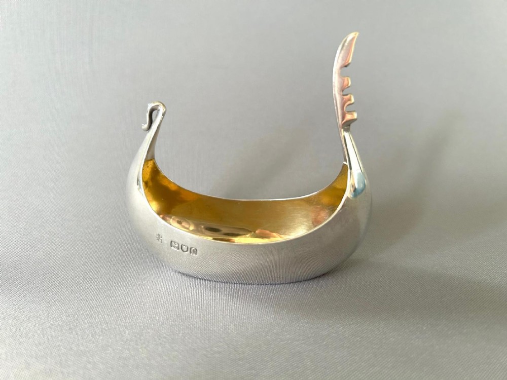 A Victorian sterling silver salt tub fashioned in the shape of a boat with a gilded interior and visible hallmarks on the exterior side.