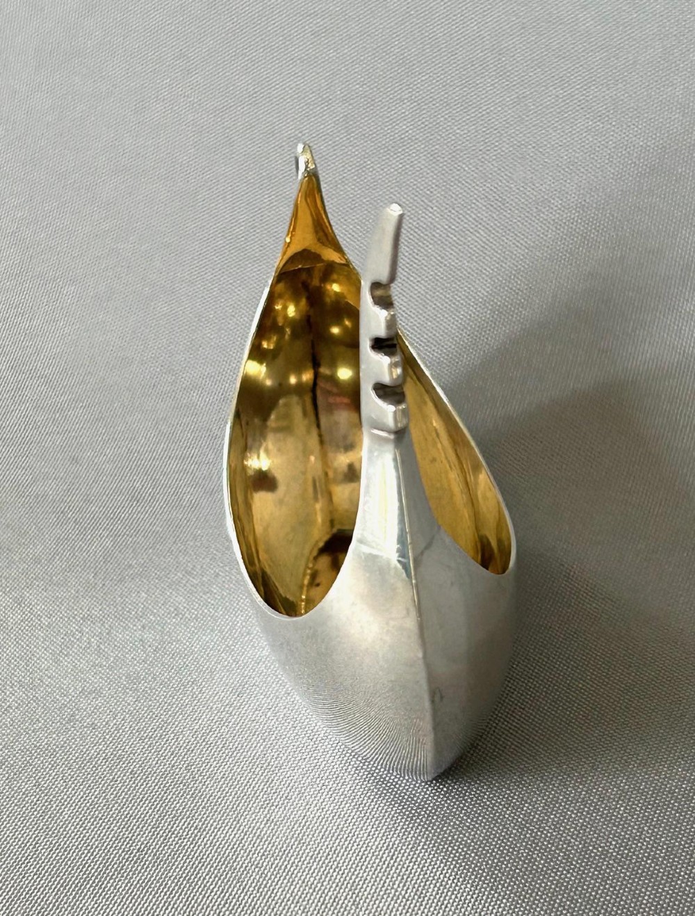 A Victorian sterling silver salt tub fashioned in the shape of a boat with a gilded interior and visible hallmarks on the exterior side. View V