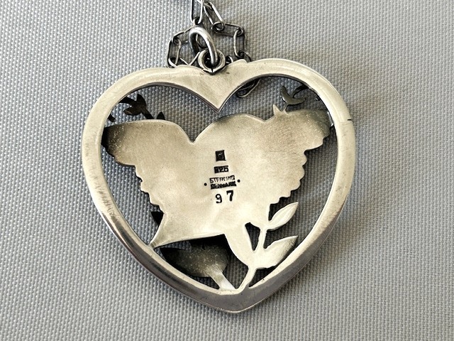 A sterling silver heart-shaped pendant featuring a pierced bird and foliage motif suspended from a link chain. View III
