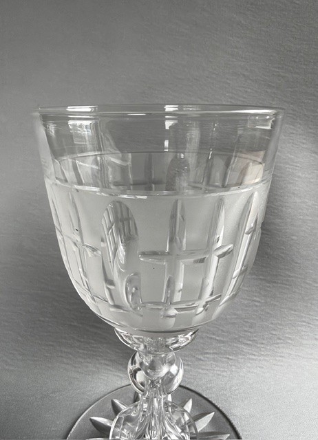 A clear Victorian cut crystal wine goblet featuring a frosted geometric pattern, faceted stem, and star-cut base. View III