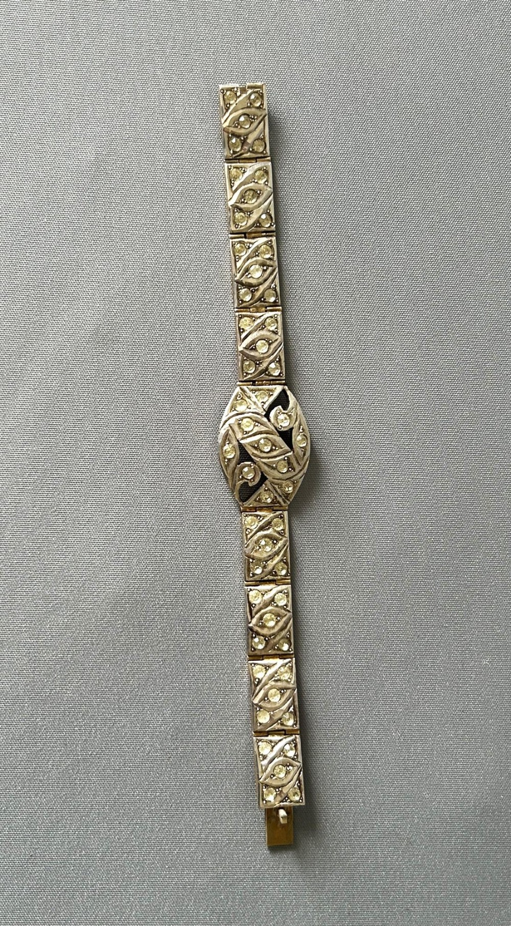 An Art Deco silver gilt panel link bracelet featuring geometric leaf motifs inlaid with small cut paste stones.