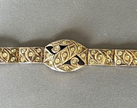 An Art Deco silver gilt panel link bracelet featuring geometric leaf motifs inlaid with small cut paste stones. View IV