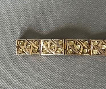 An Art Deco silver gilt panel link bracelet featuring geometric leaf motifs inlaid with small cut paste stones. View VII