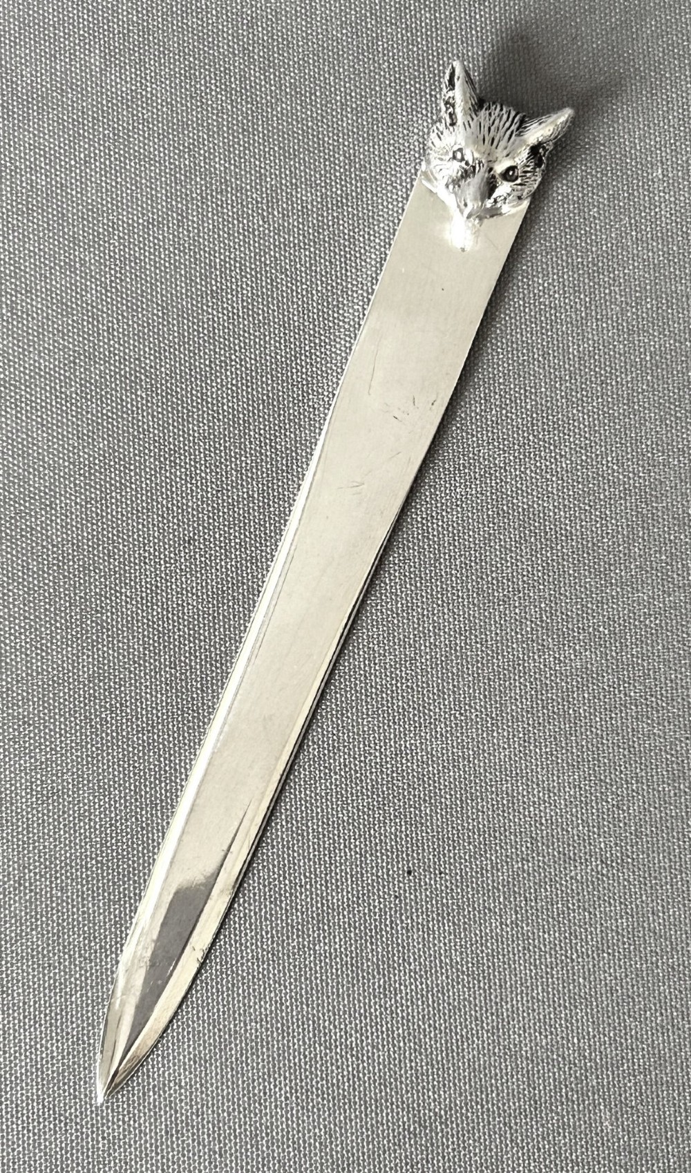 A silver letter opener featuring a tapered flat blade and a detailed cast fox head terminal.