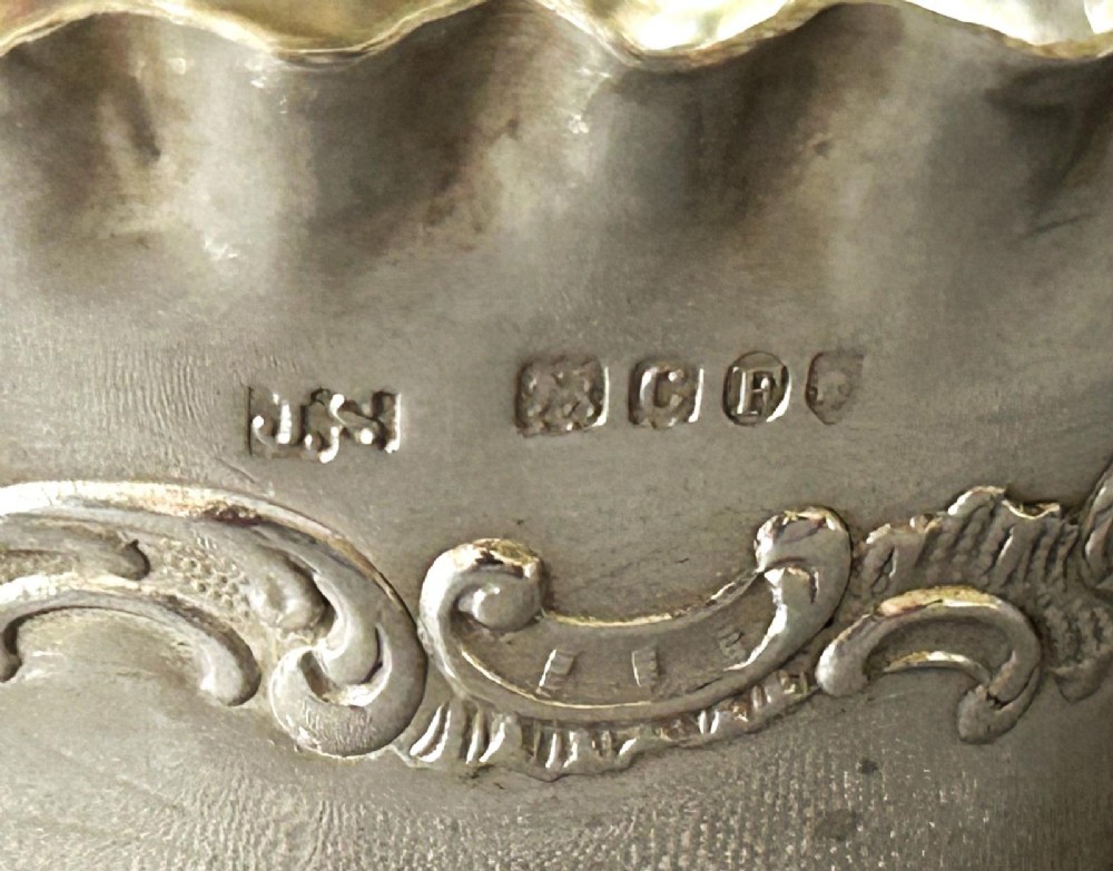 A pair of small silver bonbon baskets featuring crimped rims, embossed scrollwork motifs, and twisted overhead rope handles. View VI