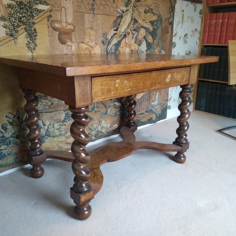 An 18th-century rectangular wooden centre table featuring elaborate floral marquetry inlay on the top, twisted legs, and a curvilinear X-frame stretcher. View XVIII