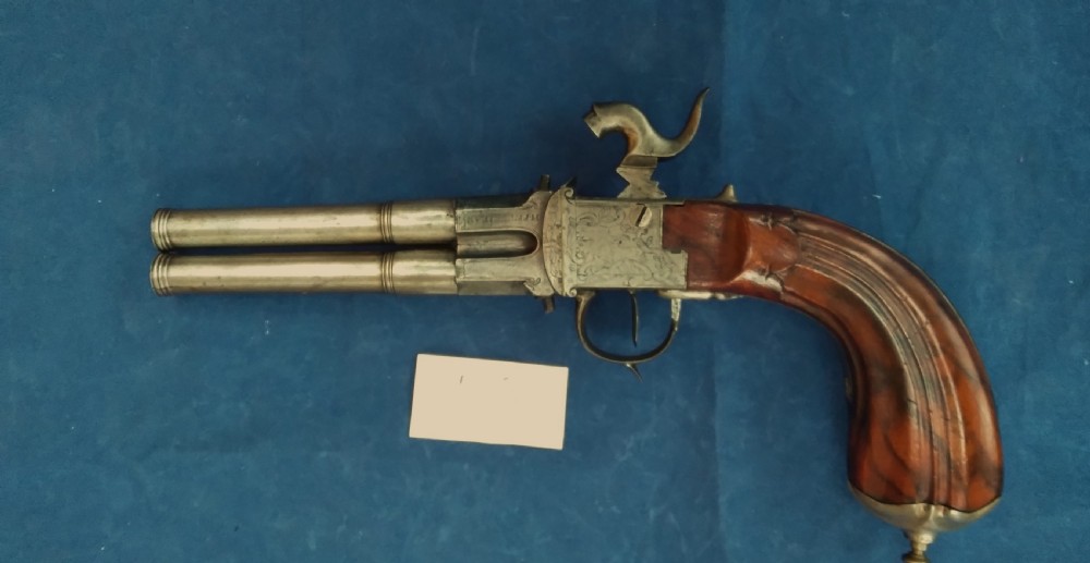 An early 19th-century revolving barrel pistol featuring twin steel barrels, an engraved lockplate, and a curved wooden grip.