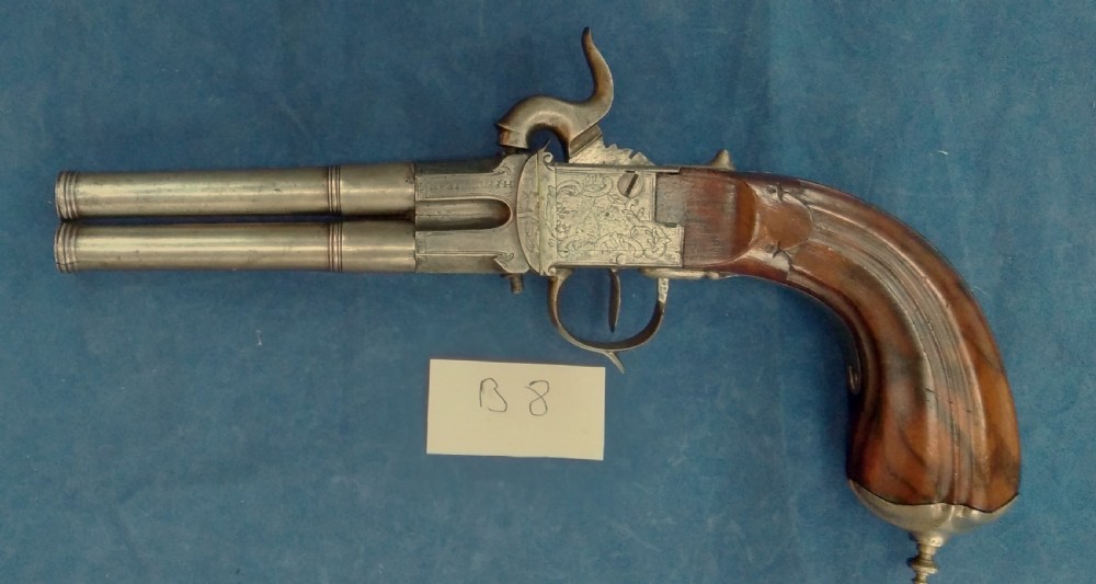 An early 19th-century revolving barrel pistol featuring twin steel barrels, an engraved lockplate, and a curved wooden grip. View II