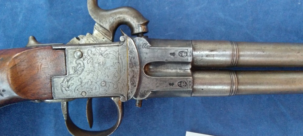 An early 19th-century revolving barrel pistol featuring twin steel barrels, an engraved lockplate, and a curved wooden grip. View IV