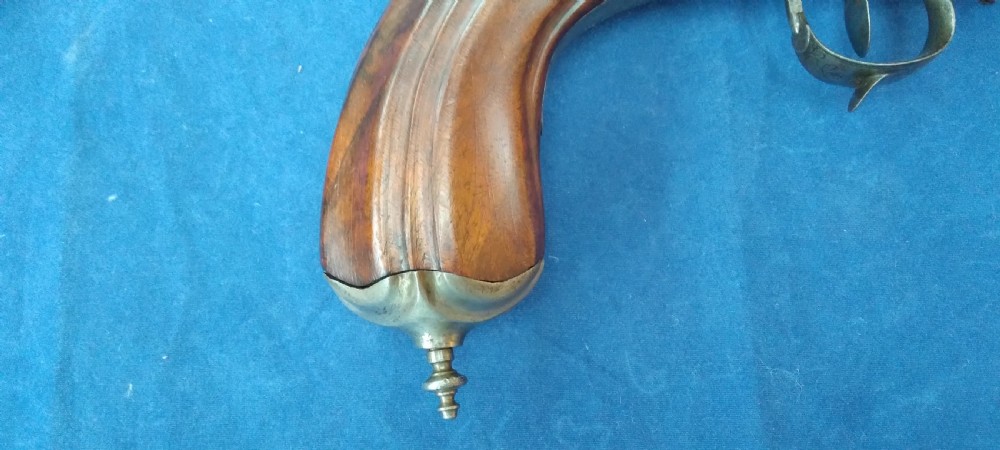 An early 19th-century revolving barrel pistol featuring twin steel barrels, an engraved lockplate, and a curved wooden grip. View V