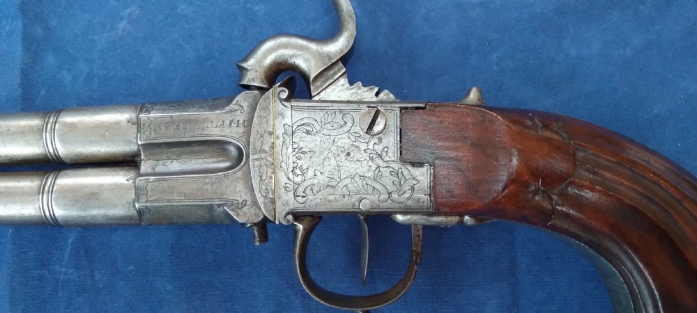 An early 19th-century revolving barrel pistol featuring twin steel barrels, an engraved lockplate, and a curved wooden grip. View VII