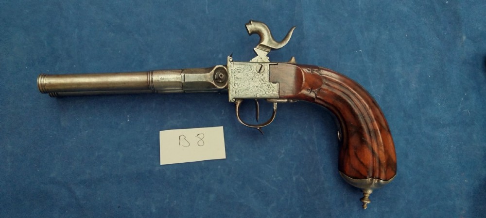 An early 19th-century revolving barrel pistol featuring twin steel barrels, an engraved lockplate, and a curved wooden grip. View IX