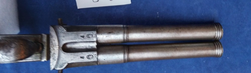 An early 19th-century revolving barrel pistol featuring twin steel barrels, an engraved lockplate, and a curved wooden grip. View XI