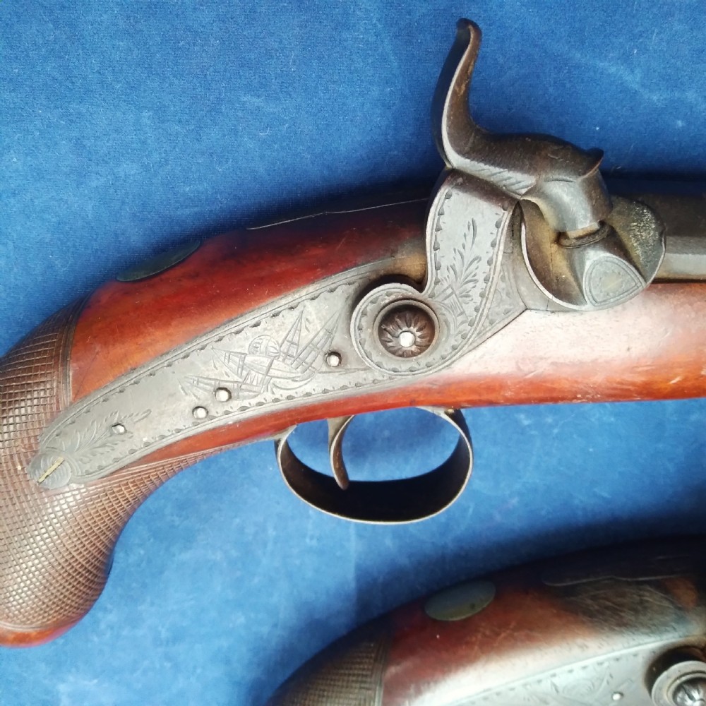 A matched pair of 19th-century percussion cap pistols featuring chequered walnut stocks, engraved steel lockplates, and brass-tipped ramrods. View II