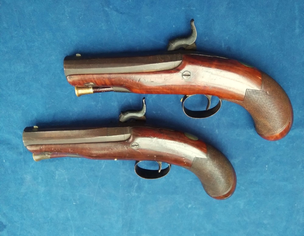 A matched pair of 19th-century percussion cap pistols featuring chequered walnut stocks, engraved steel lockplates, and brass-tipped ramrods. View IV