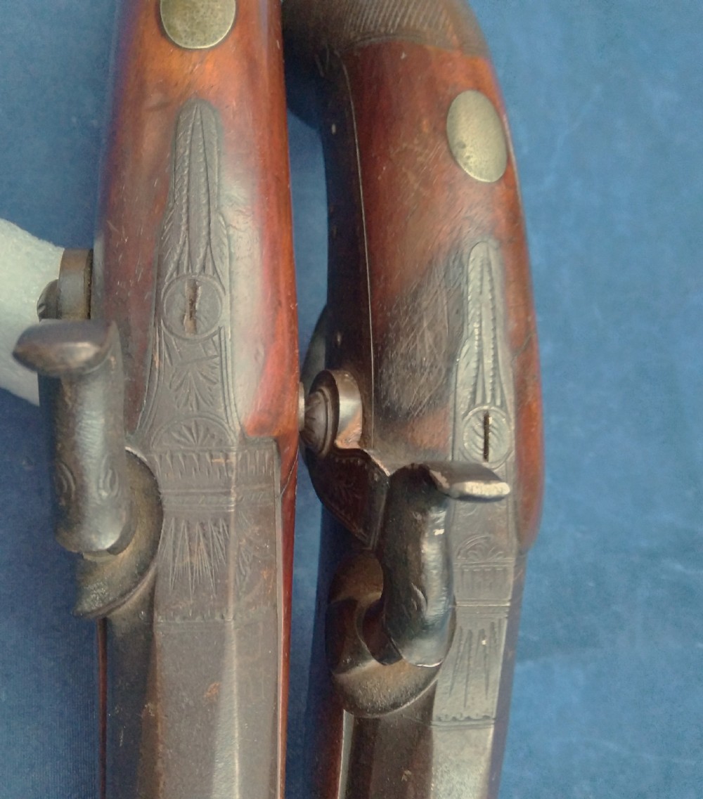 A matched pair of 19th-century percussion cap pistols featuring chequered walnut stocks, engraved steel lockplates, and brass-tipped ramrods. View VI