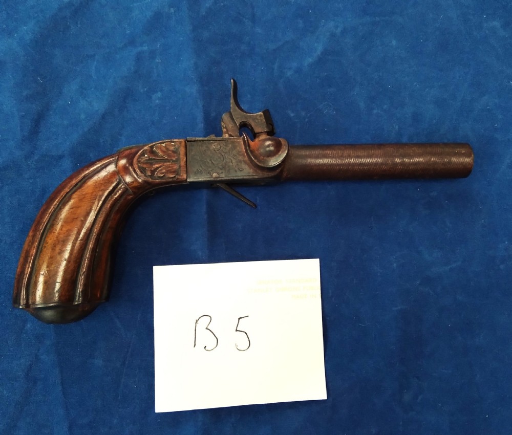 A nineteenth-century percussion cap pocket pistol with a carved walnut grip and steel barrel.