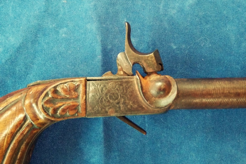 A nineteenth-century percussion cap pocket pistol with a carved walnut grip and steel barrel. View II