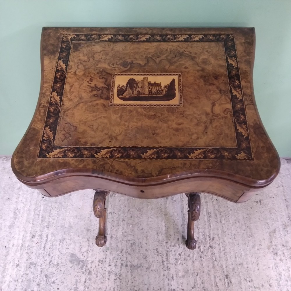 A Victorian burr walnut work table featuring a central Tunbridge ware marquetry landscape scene, serpentine edges, and turned legs with scroll feet. View II
