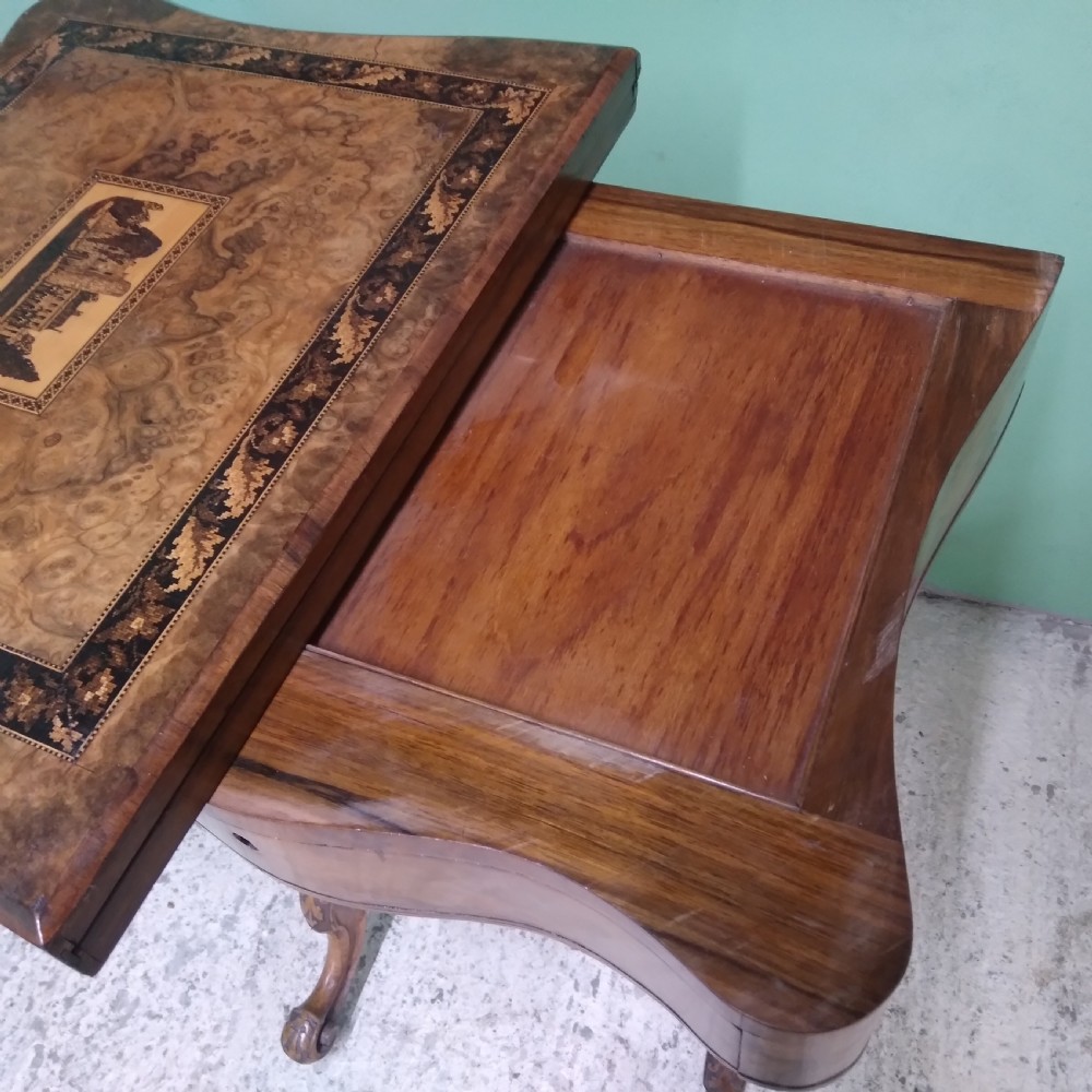 A Victorian burr walnut work table featuring a central Tunbridge ware marquetry landscape scene, serpentine edges, and turned legs with scroll feet. View VIII