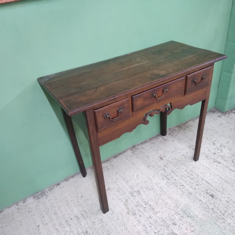 An antique fruitwood lowboy table featuring three drawers with brass drop handles, a shaped lower apron, and four square legs. View III