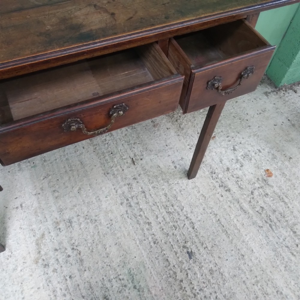 An antique fruitwood lowboy table featuring three drawers with brass drop handles, a shaped lower apron, and four square legs. View V