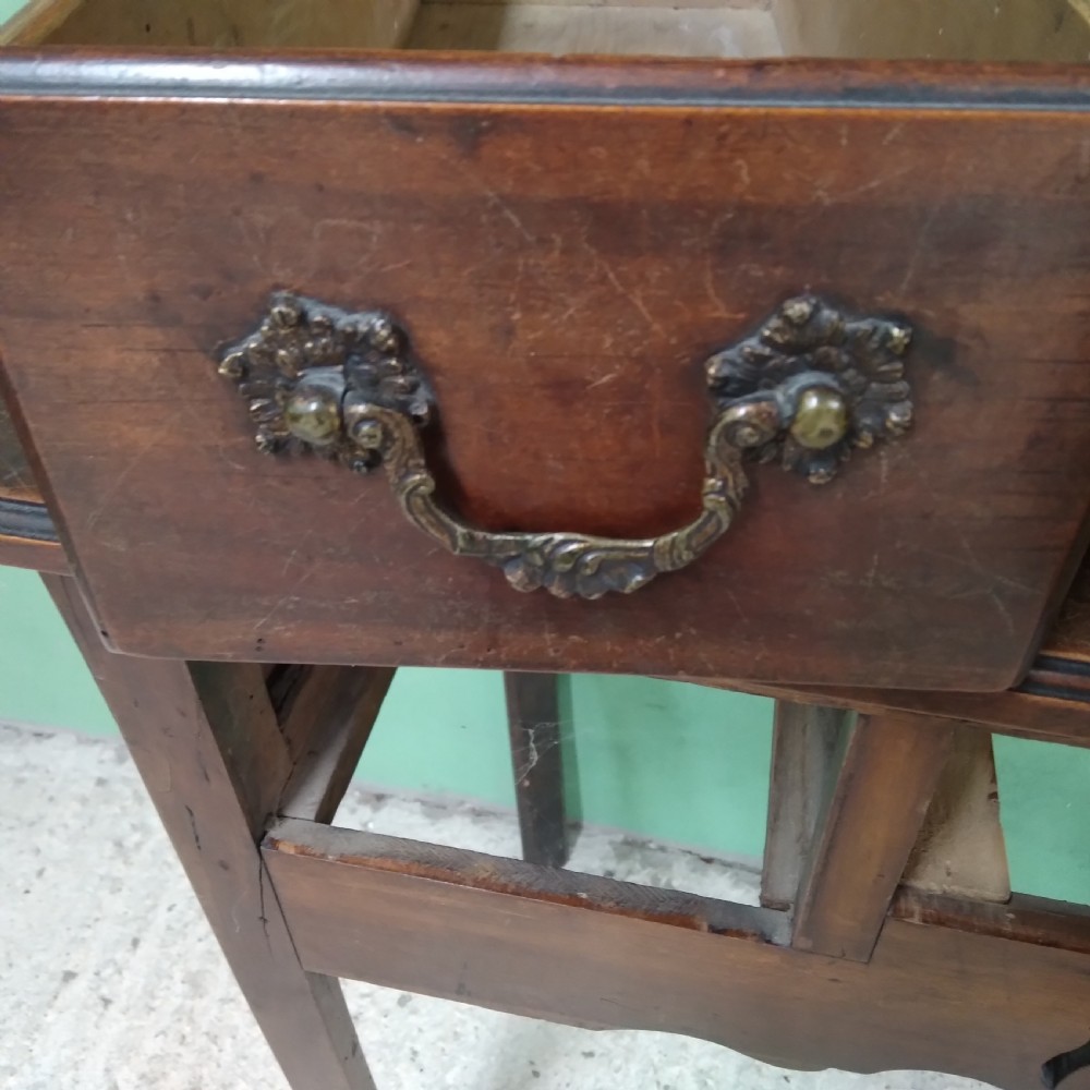 An antique fruitwood lowboy table featuring three drawers with brass drop handles, a shaped lower apron, and four square legs. View IX