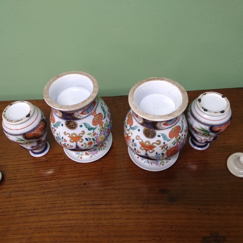 A four-piece antique Continental porcelain garniture set featuring two central urn-shaped vases and two outer stoppered bottles with cobalt blue panels and polychrome floral decoration. View V