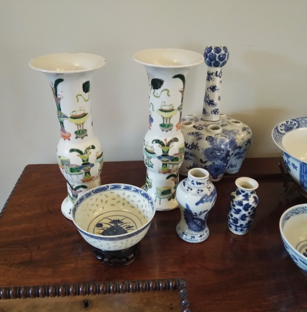 A collection of varied Chinese blue and white and polychrome porcelain vases, bowls, and jars displayed along a dark wood sideboard. View II