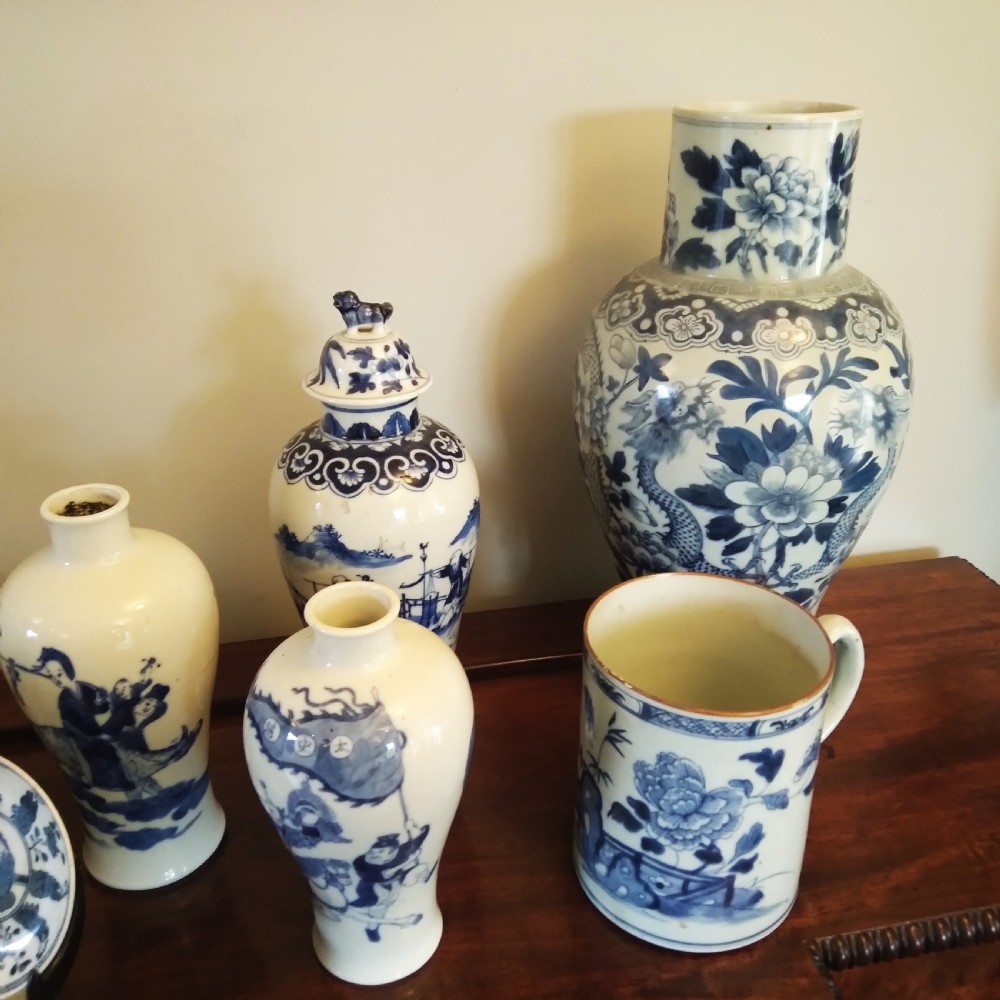 A collection of varied Chinese blue and white and polychrome porcelain vases, bowls, and jars displayed along a dark wood sideboard. View V