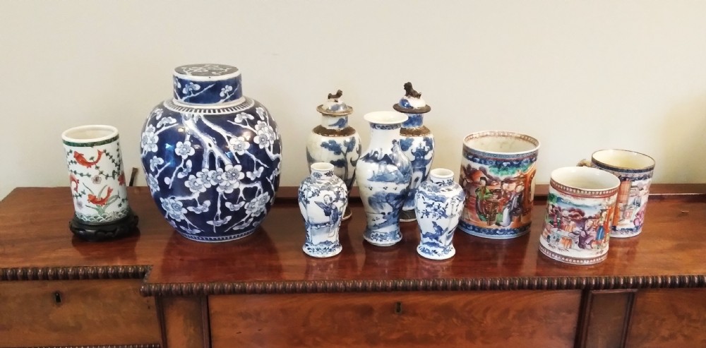 A collection of varied Chinese blue and white and polychrome porcelain vases, bowls, and jars displayed along a dark wood sideboard. View XXV