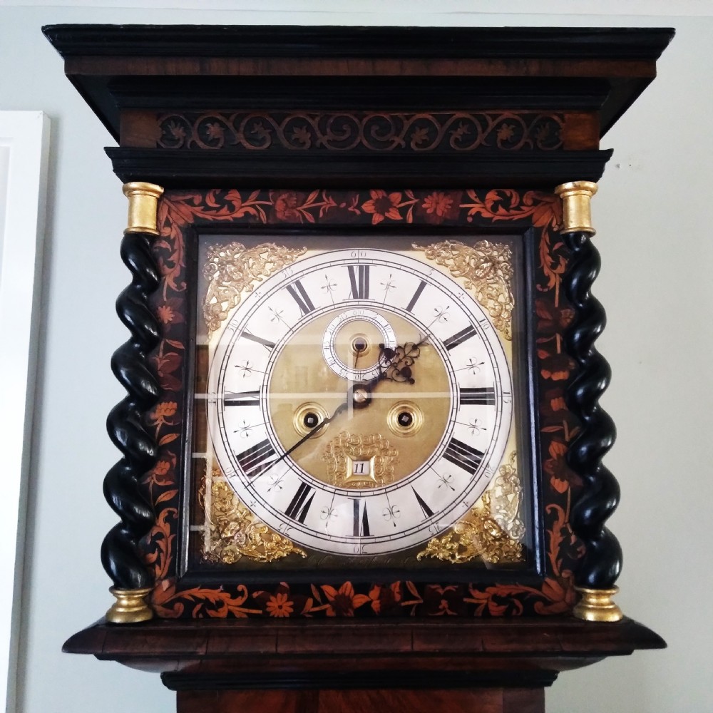 A 17th-century walnut longcase clock featuring floral marquetry inlays, a square brass dial, and twisted hood columns. View II