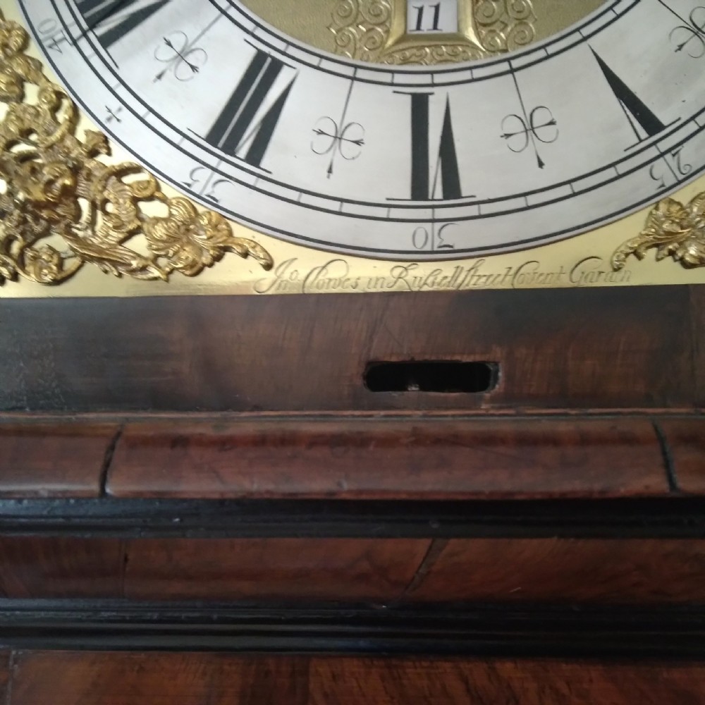 A 17th-century walnut longcase clock featuring floral marquetry inlays, a square brass dial, and twisted hood columns. View III
