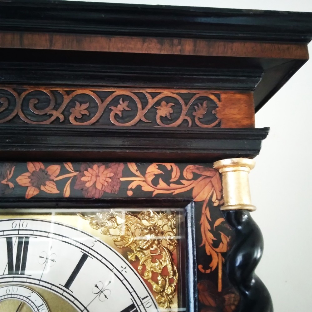 A 17th-century walnut longcase clock featuring floral marquetry inlays, a square brass dial, and twisted hood columns. View IV