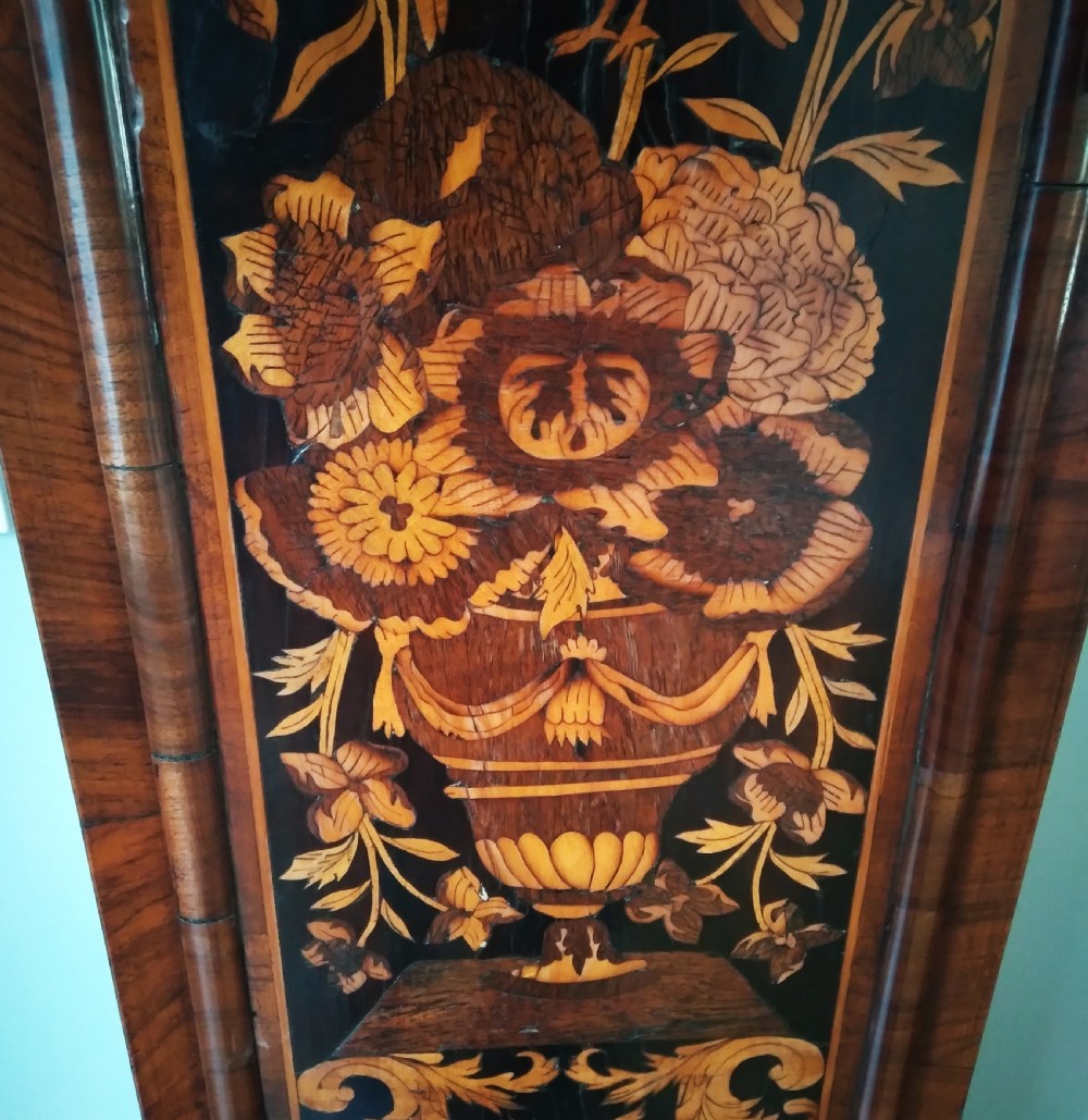A 17th-century walnut longcase clock featuring floral marquetry inlays, a square brass dial, and twisted hood columns. View VI