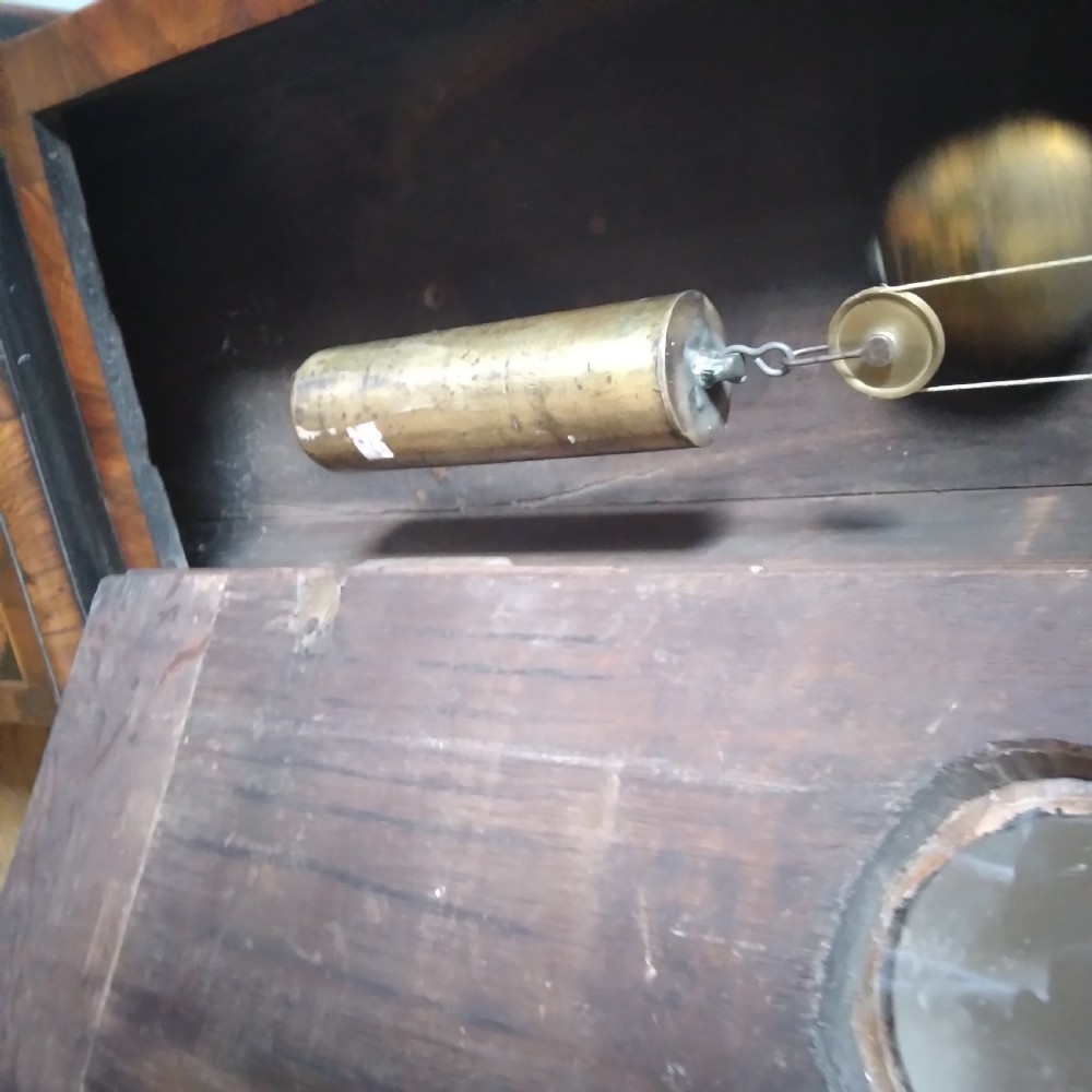 A 17th-century walnut longcase clock featuring floral marquetry inlays, a square brass dial, and twisted hood columns. View XII