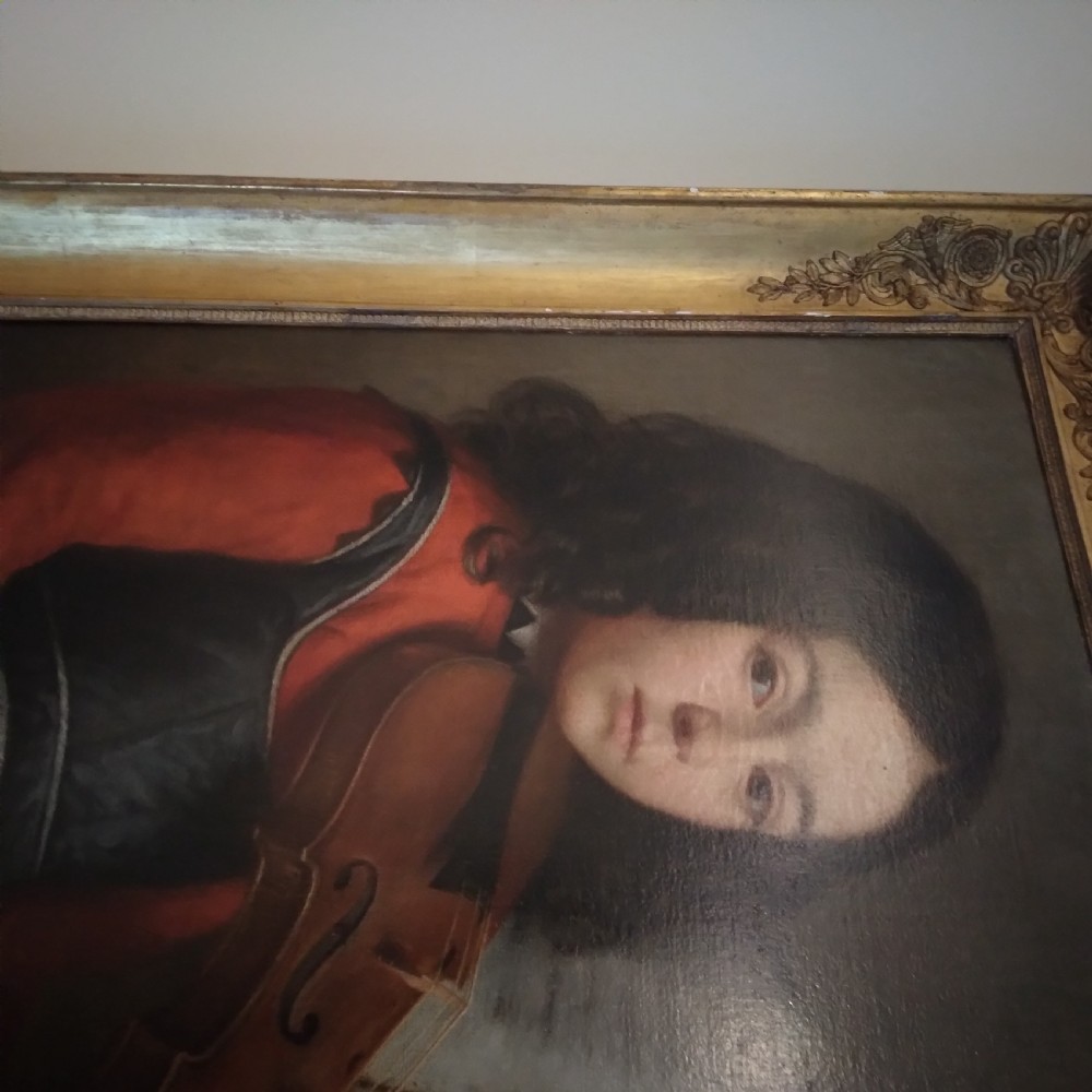An antique oil portrait on canvas showing a young person with long dark hair playing a violin, set in a carved gilt frame. View II