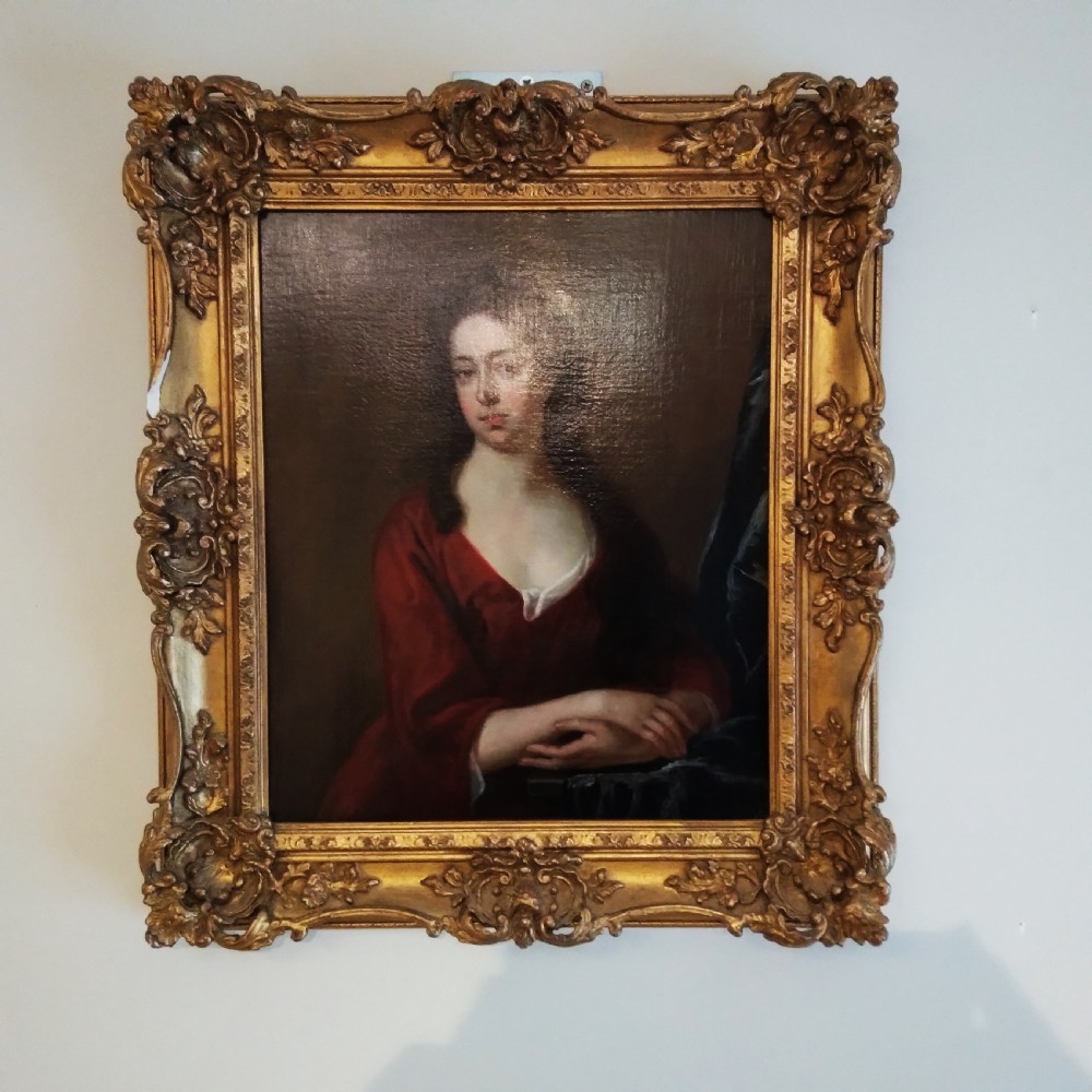 An 18th-century oil portrait of a woman in a red gown set within a carved giltwood frame. View II