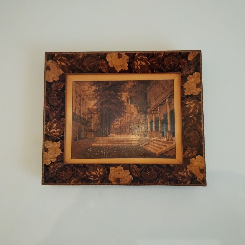 A rectangular Victorian Tunbridge Ware wooden wall plaque featuring a central tessellated architectural scene surrounded by a floral mosaic marquetry frame.