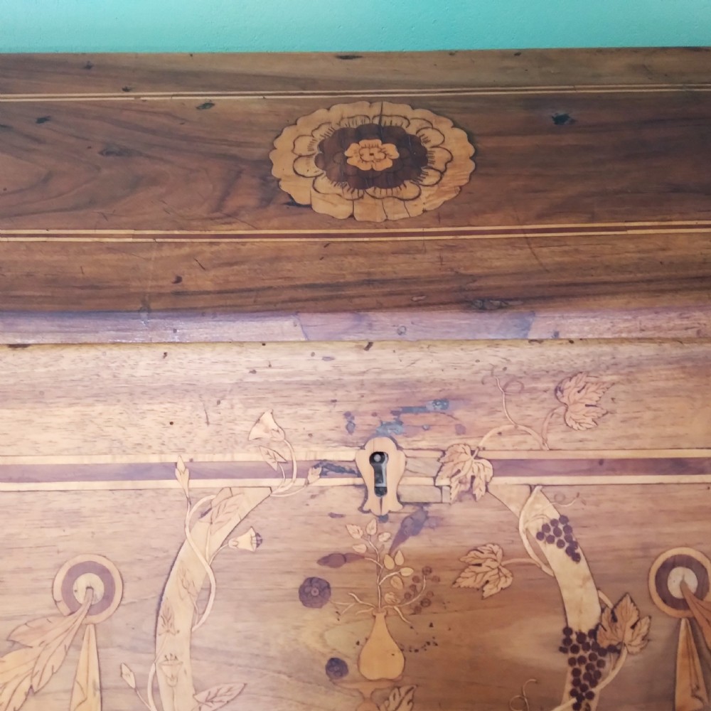 An 18th-century fruitwood writing bureau featuring a sloping fall-front lid with decorative marquetry garland inlays and two drawers below. View IV