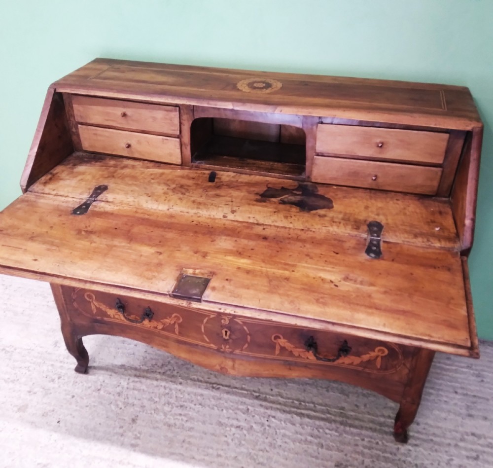 An 18th-century fruitwood writing bureau featuring a sloping fall-front lid with decorative marquetry garland inlays and two drawers below. View XII