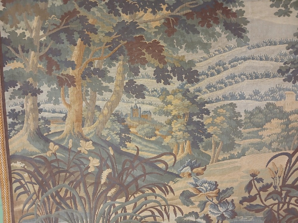 A late nineteenth-century French woven verdure tapestry depicting a dense forest landscape with trees, foreground foliage, and a distant castle under a cloudy sky. View II
