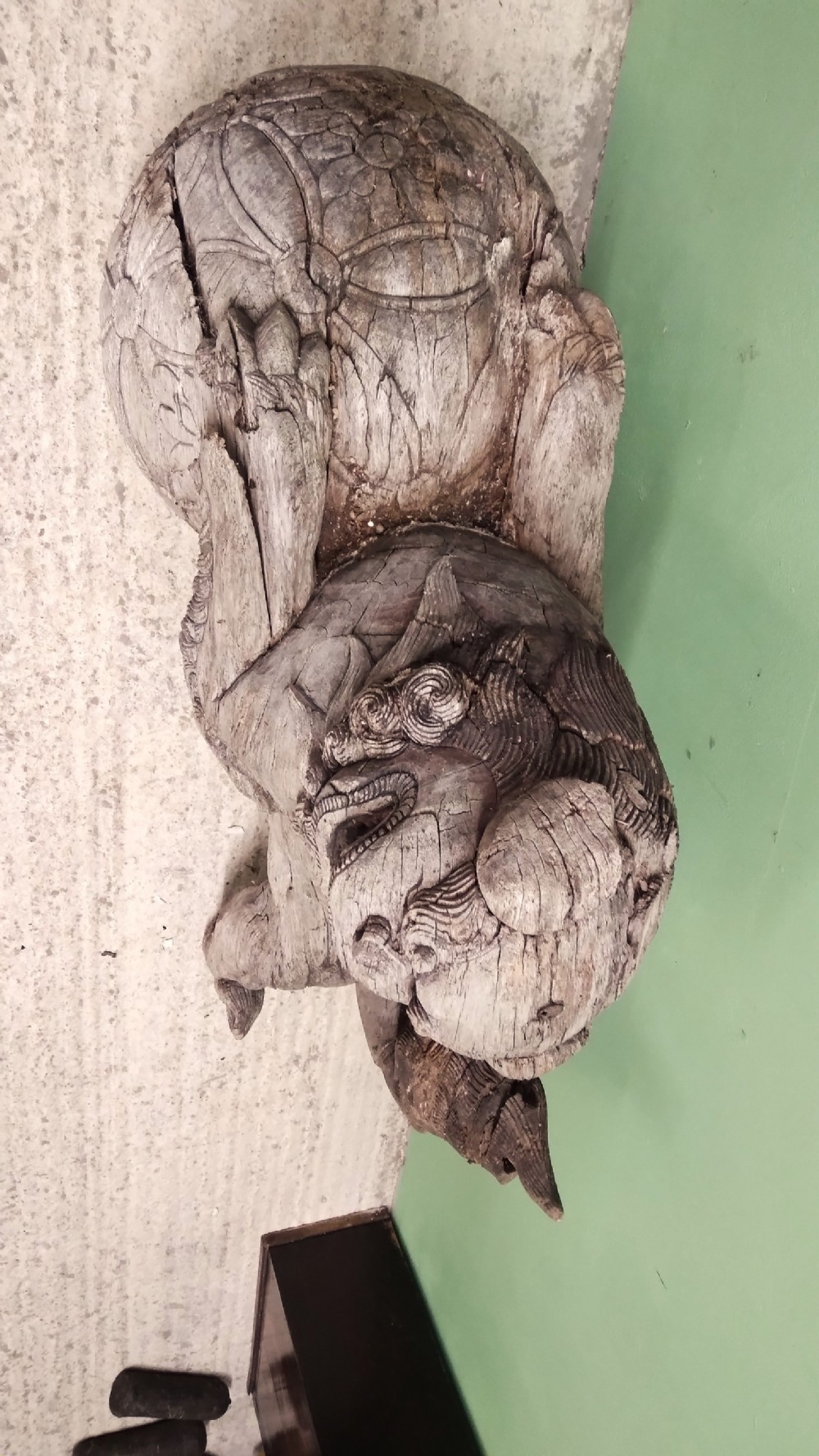 A weathered hand-carved wooden Chinese guardian lion resting its front paw on a decorative brocade ball. View III