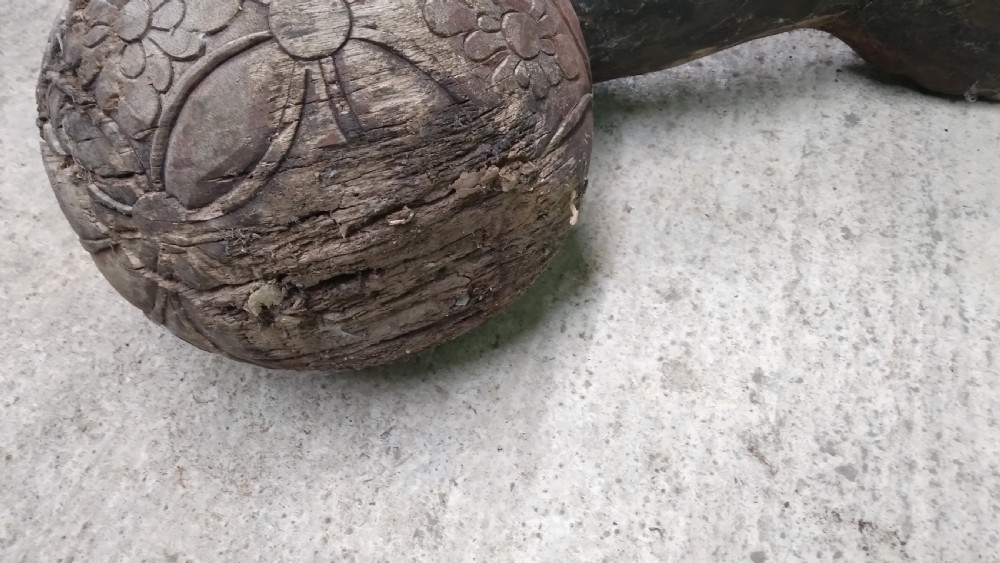 A weathered hand-carved wooden Chinese guardian lion resting its front paw on a decorative brocade ball. View VI